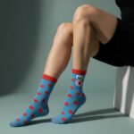 Blue playful polka-dot socks with red dots and a cartoon face design on model’s legs by EmotiForce Australia